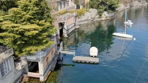 Un cours d’eau paisible, avec un quai, un petit bateau et un pont.