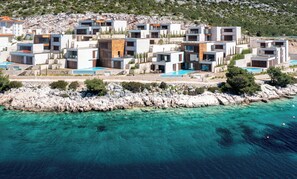 A coastal resort with modern villas, a rocky shoreline, and clear turquoise waters. - Figs and Olives (Primošten Burnji)