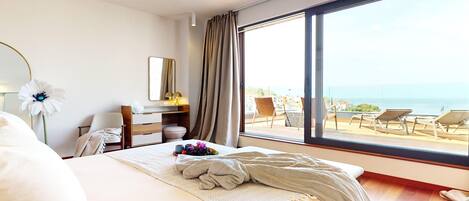 A hotel room with a large window, a bed, a desk, and a chair.