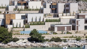 Ein Küstenwohngebiet mit moderner Architektur, einer felsigen Uferlinie und Booten, die am Wasser liegen.