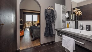 Ein modernes Badezimmer mit einem großen Waschbecken, dunklem Holzboden und einem Bademantel, der an der Wand hängt.