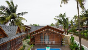 Un complexe hôtelier doté de chalets en bois, d’une piscine et de palmiers.