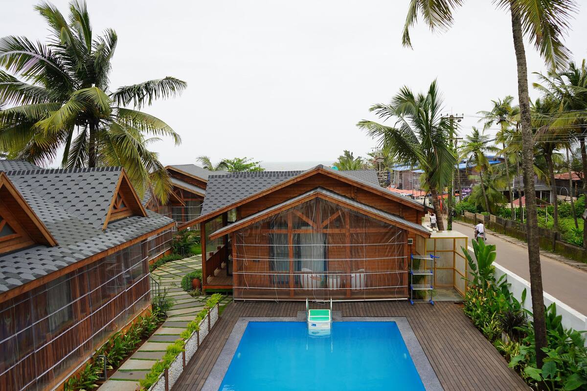 Ein Resort mit Holzhütten, einem Schwimmbad und Palmen.