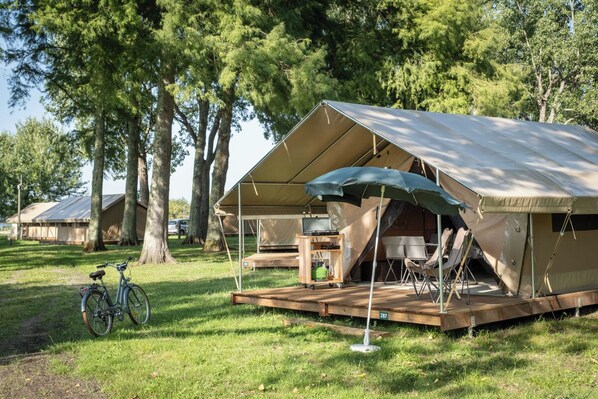 Un camping con tiendas de campaña, una bicicleta y una terraza de madera.