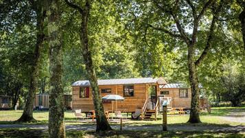 Une cabane en bois avec un porche, entourée d’arbres.