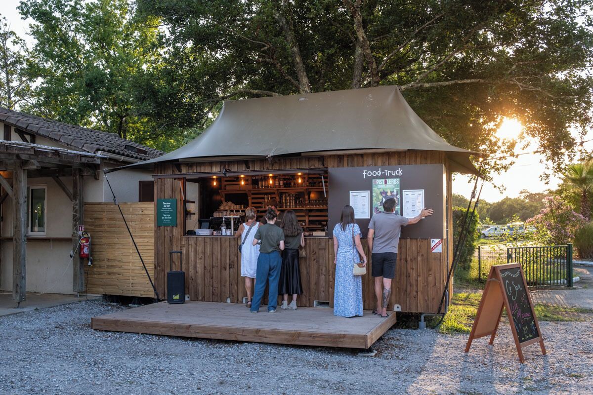 Een rustieke foodtruck met een houten buitenkant en een luifel, met een menubord en een prikbord.
