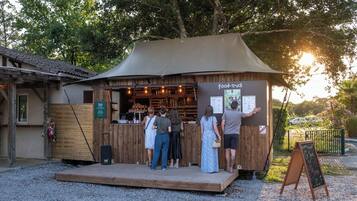 Un camion-restaurant au style rustique, avec une façade en bois et un auvent, doté d’un panneau affichant le menu et d’un tableau noir servant de panneau d’affichage.