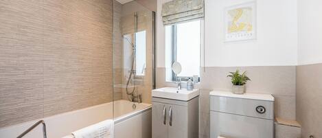 A modern bathroom with a glass-enclosed shower, a sink with a mirror, and a toilet.