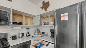 A modern kitchen with a stainless steel refrigerator, a built-in microwave, and a coffee maker.