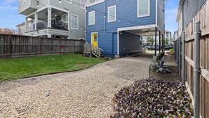 A residential area with two-story houses, a gravel driveway, and a wooden fence.