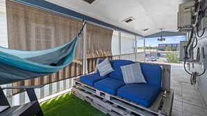 Een balkon met een blauwe bank, een hangmat en uitzicht op de straat.