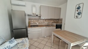 Eine kleine Küche mit Kühlschrank, Herd, Spüle und Esstisch.