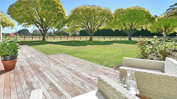 A wooden deck with wicker furniture and a grassy lawn. - Relaxing Rural Getaway – Near Kaiapoi Lakes, Room to Roam (Kaiapoi)