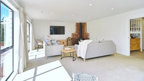 A modern living room with a fireplace, two sofas, a TV, and a large window. - Relaxing Rural Getaway – Near Kaiapoi Lakes, Room to Roam (Kaiapoi)