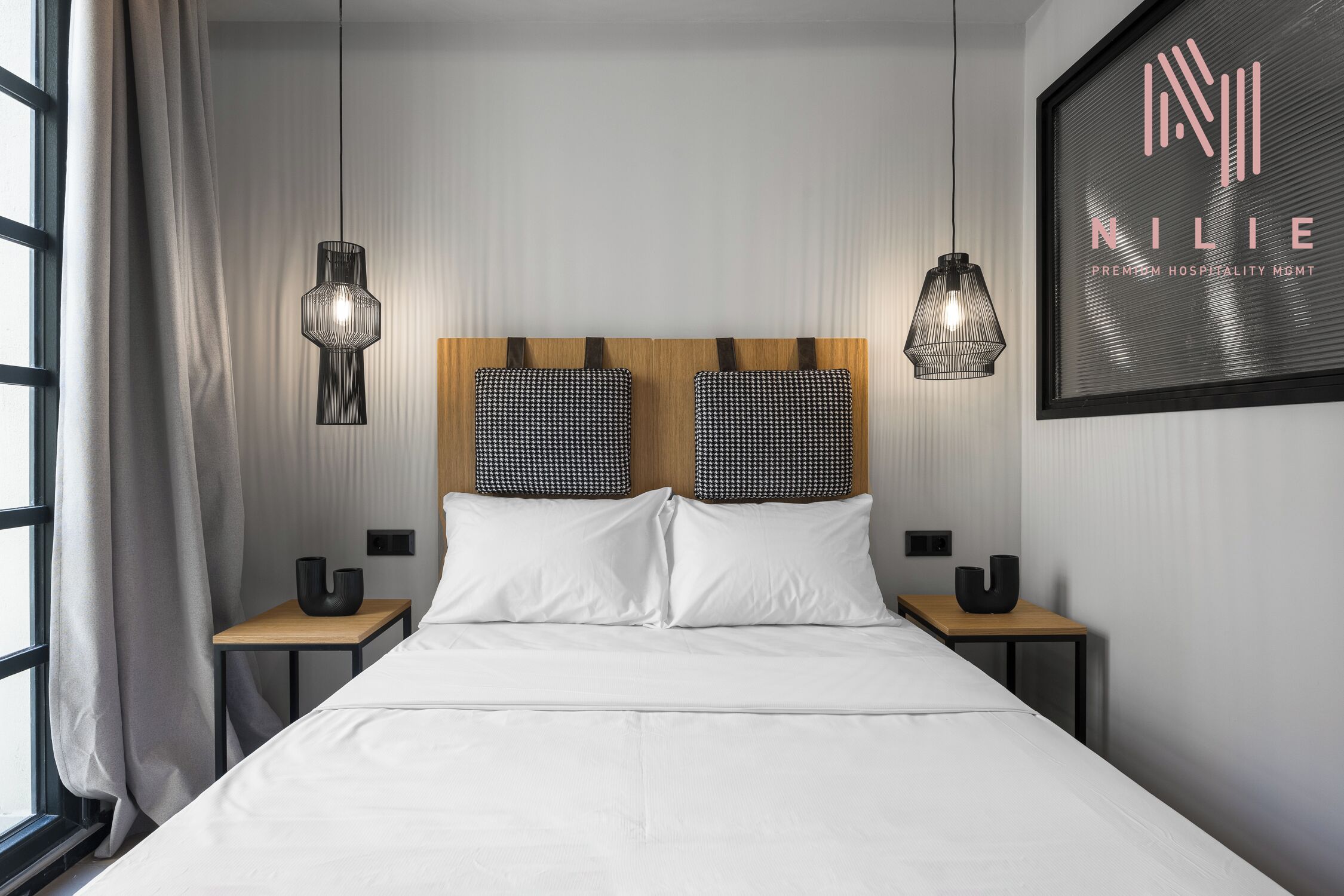 A modern hotel room with a large bed, two bedside tables, and a headboard with a unique pattern.