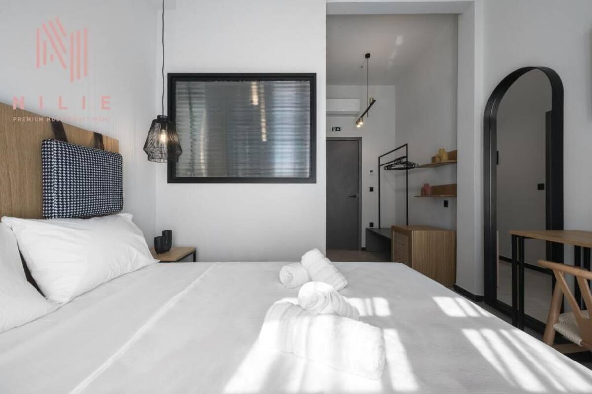 Una habitación de hotel moderna con una cama bien hecha, un espejo grande y un cabecero de madera.