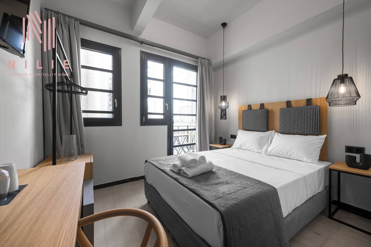 Una habitación de hotel moderna con una cama grande, un escritorio y un balcón.