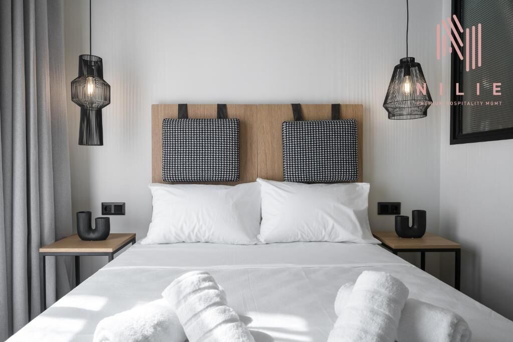 Quarto de hotel moderno com uma cama grande, duas mesas de cabeceira e painéis decorativos na parede.