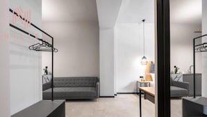 A modern interior with a grey sofa, a wooden table, and a hanging light fixture.