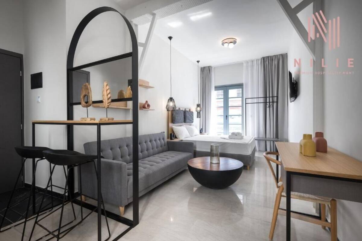Una habitación de hotel moderna con sofá, una mesa de comedor y una pequeña cocina.