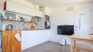 A compact kitchen with white cabinets, a tiled backsplash, a wooden countertop, and a built-in oven. - Meadows Edge (Truro)