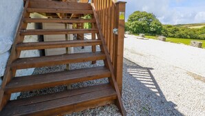 A wooden staircase leading to a building with a caution sign. - Meadows Edge (Truro)
