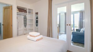 A bedroom with a bed, a wardrobe, and a view of the outside. - Meadows Edge (Truro)