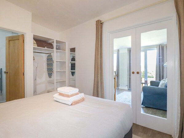 A bedroom with a bed, a wardrobe, and a view of the outside.