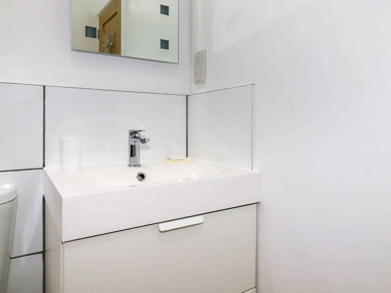 Un baño moderno con un lavabo blanco, un espejo encima y una toalla colgada en la pared.
