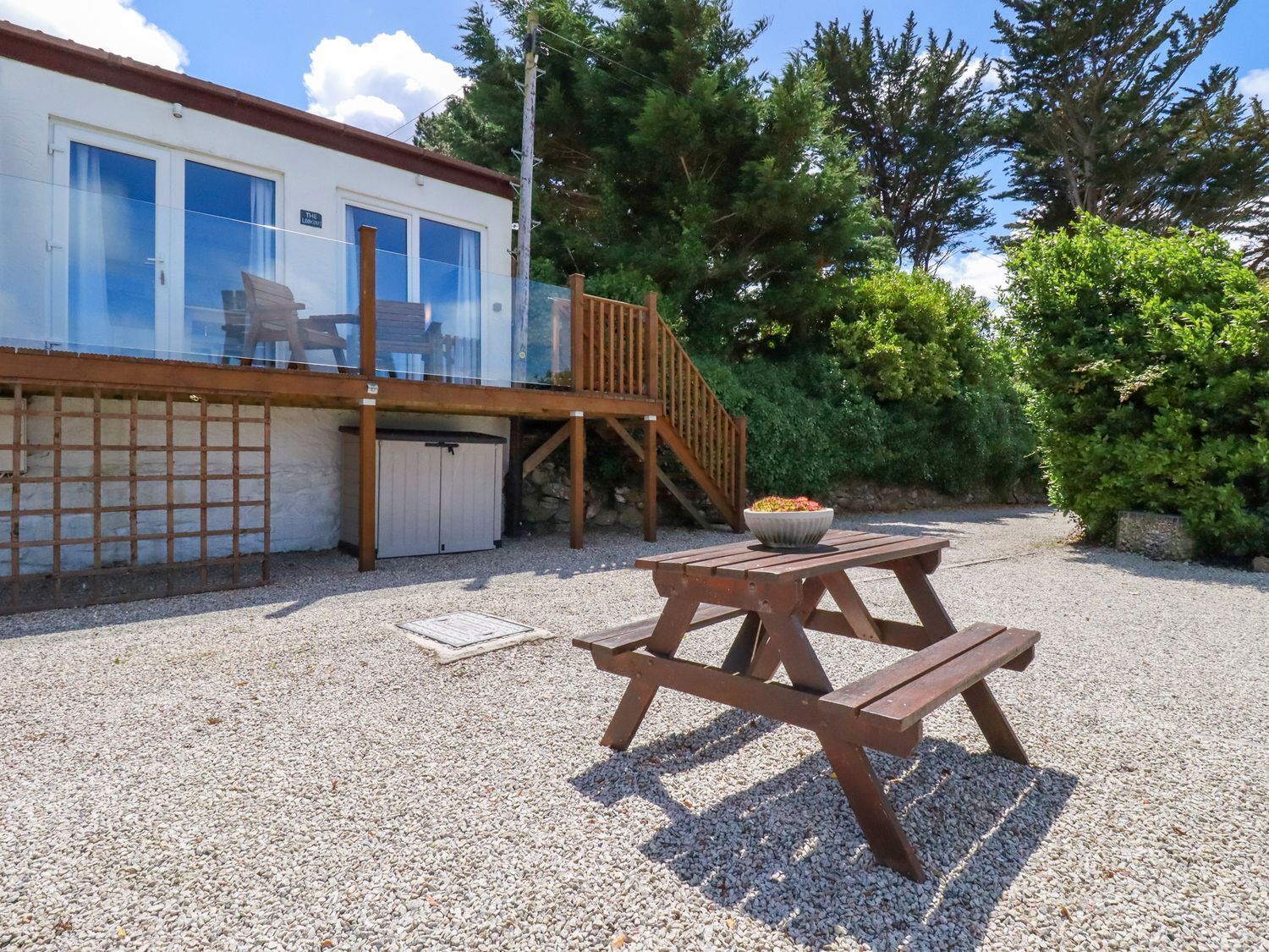 A building with a deck, a covered outdoor seating area, and a gravel ground.