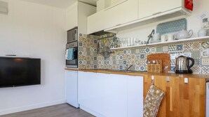 Una cocina moderna con armarios blancos, un protector contra salpicaduras de azulejos y una encimera de madera.
