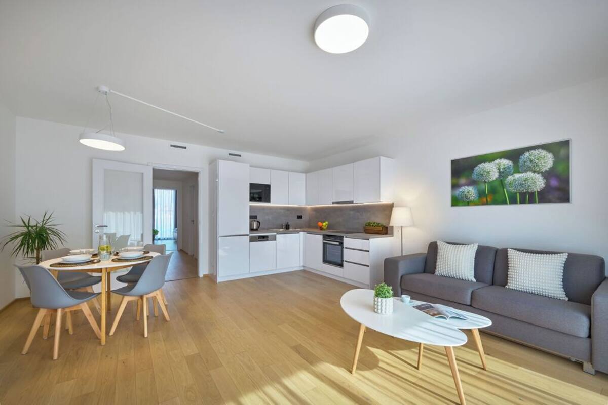 A modern living room with a grey sofa, a coffee table, and a dining area with chairs and a table.