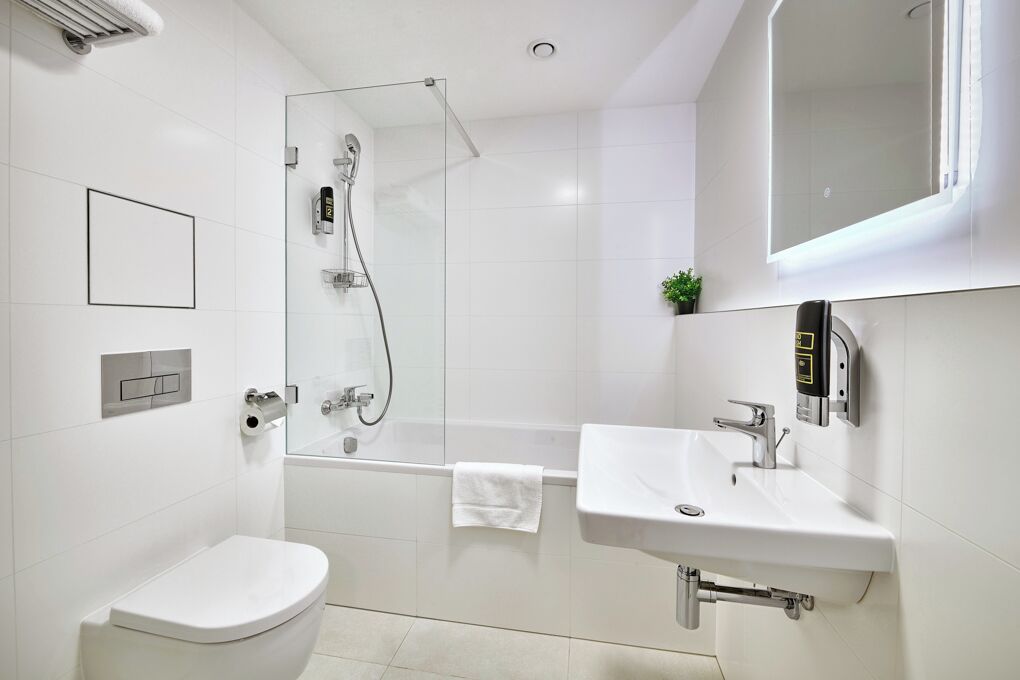 A modern bathroom with a glass-enclosed shower, a white sink, and a toilet.
