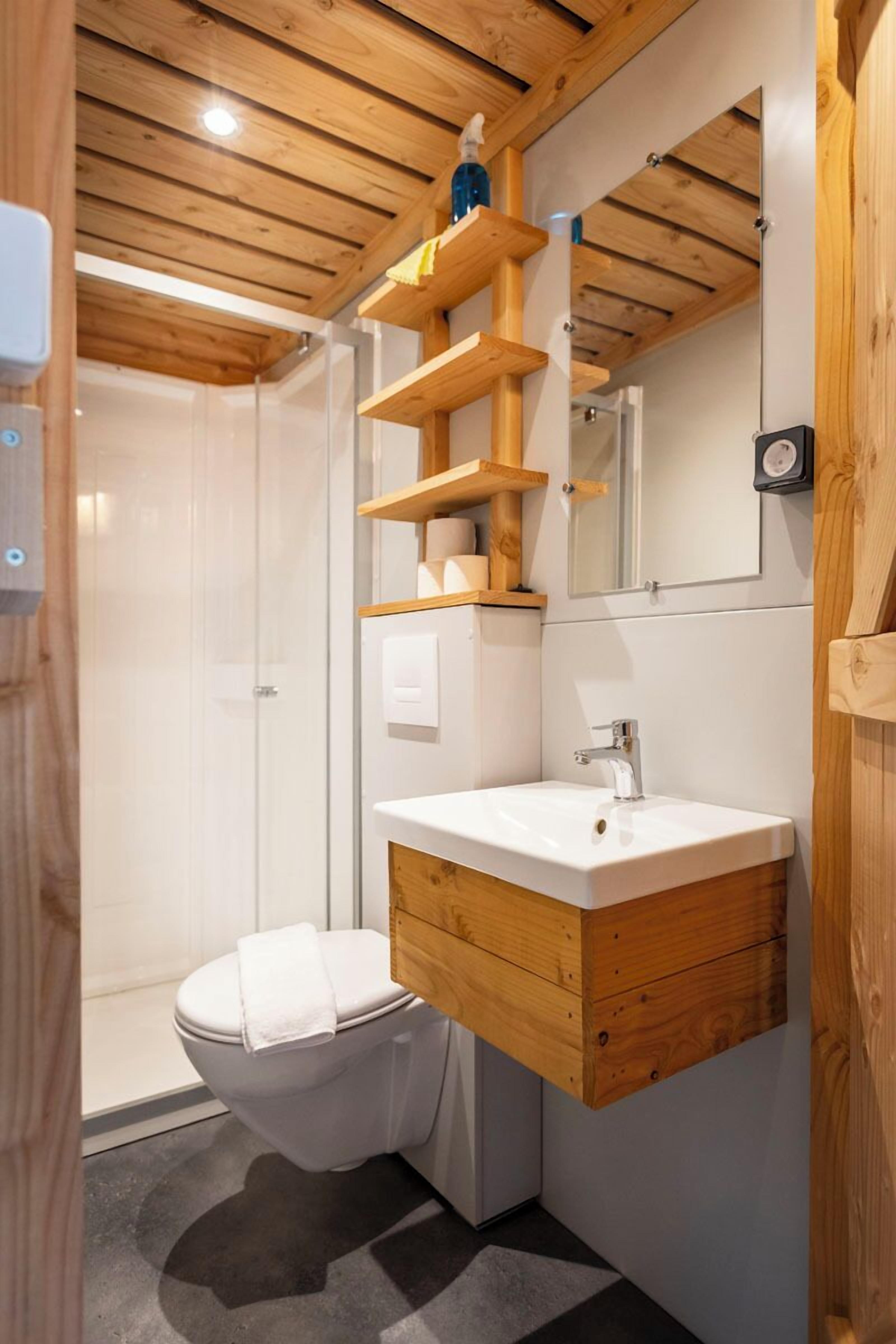 Un baño moderno con tocador de madera, lavamanos blanco y inodoro.