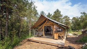 Una cabaña de madera con techo triangular, un balcón y una zona de comedor.