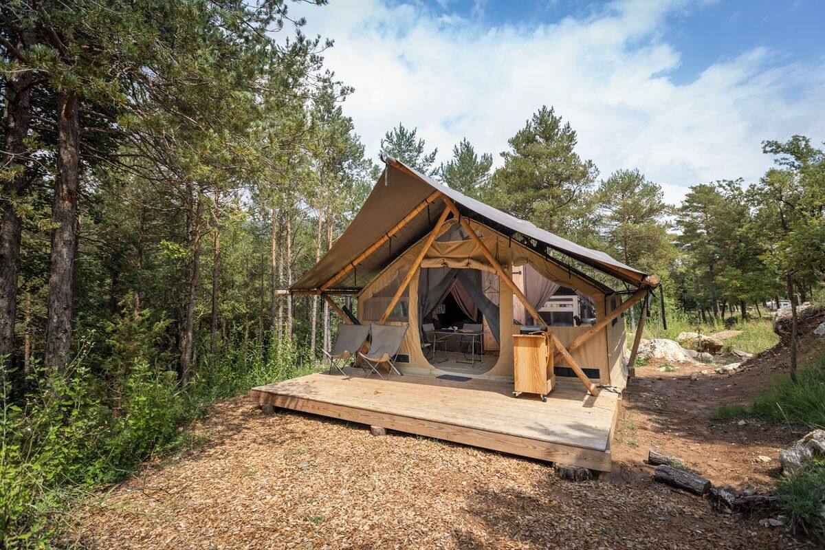 Una cabaña de madera con techo triangular, un balcón y una zona de comedor.