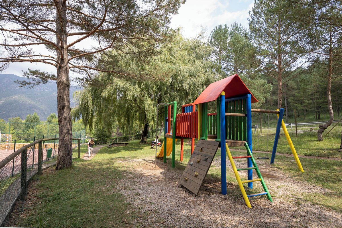 A playground with a climbing structure, slides, and a fenced area.