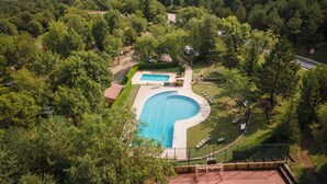 Un barrio residencial con piscina rodeada de abundante vegetación y montañas al fondo.