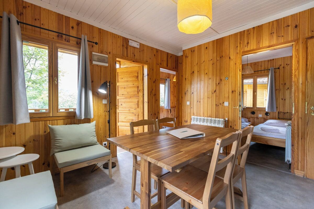 Una baita di legno con un tavolo da pranzo, sedie, una panca e un letto.