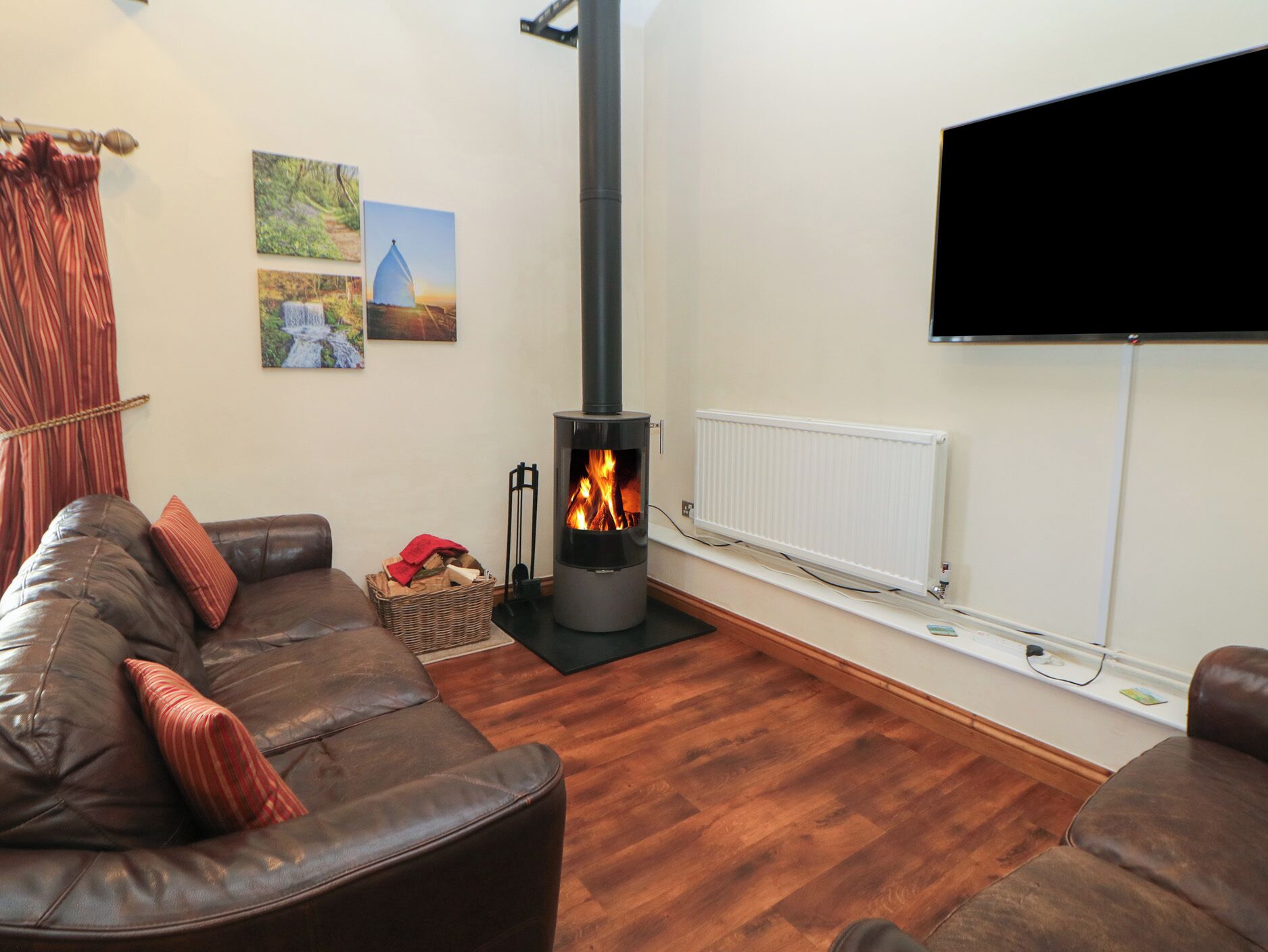 Una sala de estar con chimenea, un sofá, un televisor y un radiador.