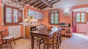 A kitchen with wooden cabinets, a dining table, chairs, a stove, and a microwave. - La Vecchia Fornace La Piastra Apartments (Abetone Cutigliano)