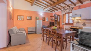 A cozy kitchen with wooden beams, a dining table, chairs, a sofa, and a refrigerator. - La Vecchia Fornace La Piastra Apartments (Abetone Cutigliano)