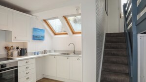 A modern kitchen with white cabinets, a built-in oven, and a skylight. - 5 Sea View Street (Cemaes Bay)