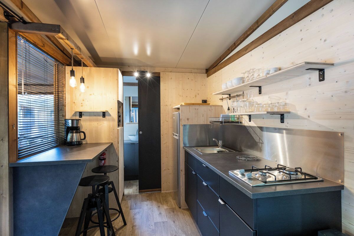 A modern kitchen with a gas stove, stainless steel appliances, wooden accents, and a bar area with stools.