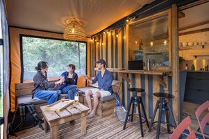 A cozy interior with a wooden bench seating area, a bar with stools, and a large window providing a view of the outdoors.