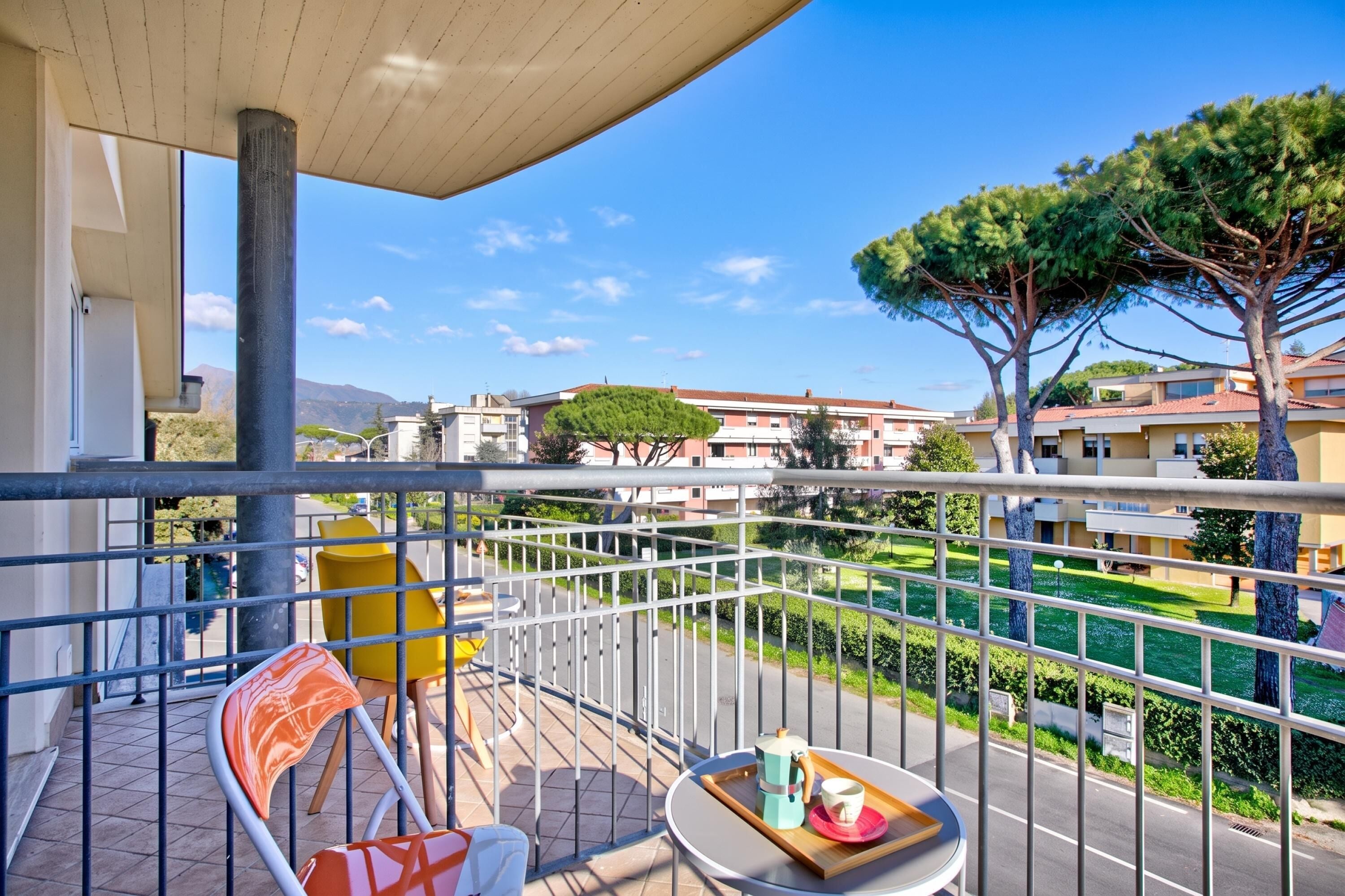 A balcony with a table, chairs, and a view of a residential area.