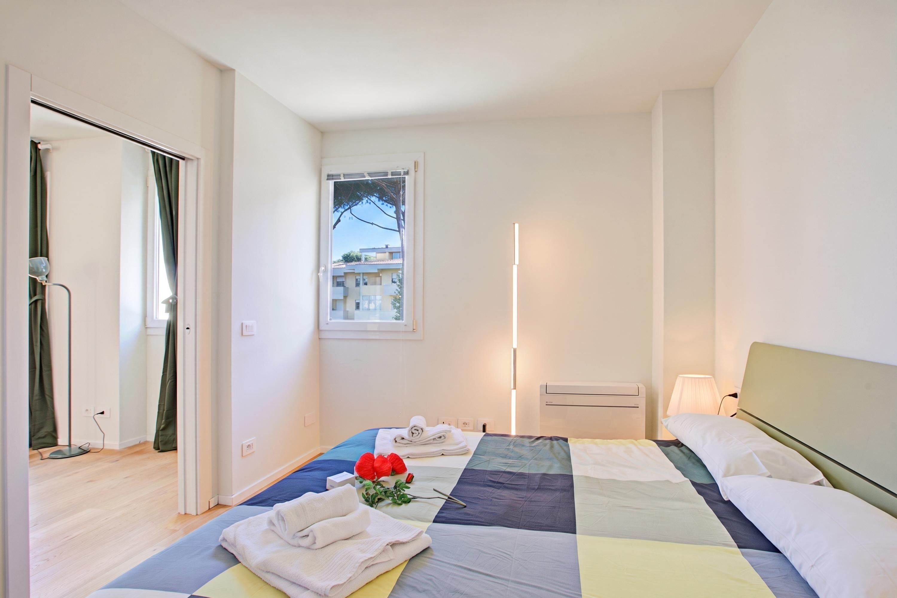 Een hotelkamer met een bed, een raam, een nachtkastje en een lamp.