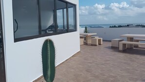 A modern building with a large window overlooking a patio area with outdoor seating and a cactus.