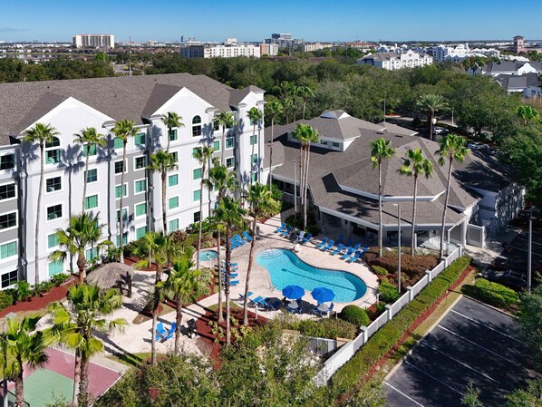Un hotel con piscina, palmeras y vistas a la ciudad.