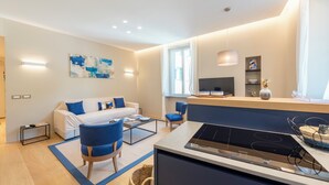 A modern living room with a sofa, chairs, a coffee table, and a kitchen area with a stove. - A dreamlike apt in Piazzetta Portofino (Portofino)